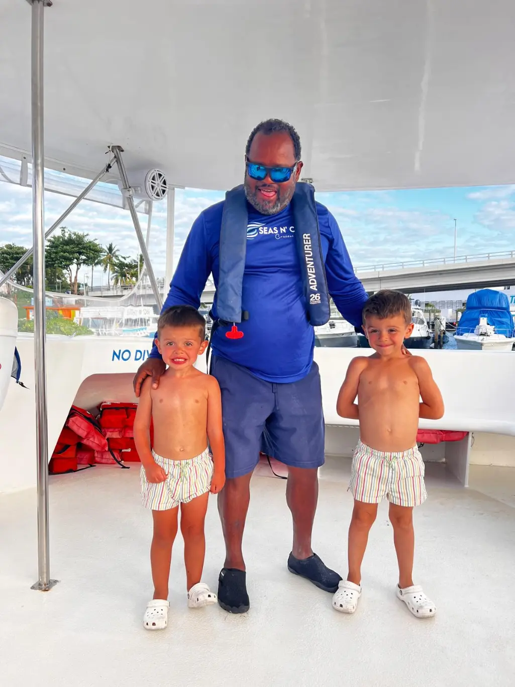 Seas N' Cays crew member in a branded blue shirt welcoming guests aboard the catamaran in Nassau