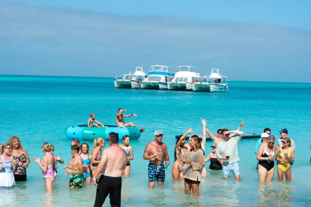 Guests swimming and playing in the turquoise water beside a Seas N' Cays catamaran